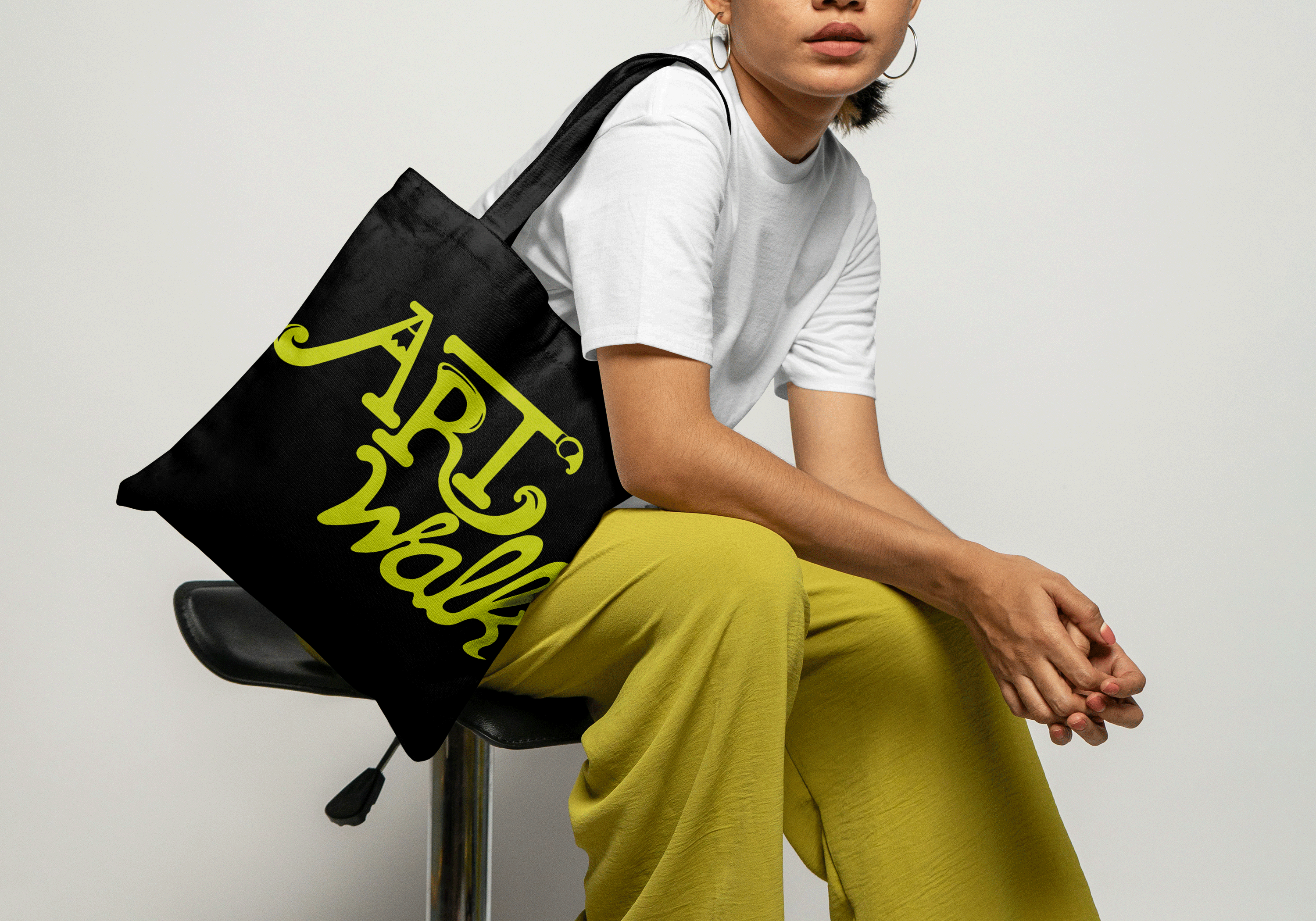 a girl wearing green pants with a black tote bag with a green ArtWalk logo on it